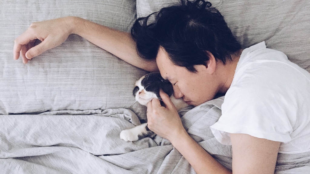 A man sleeping with a cat
