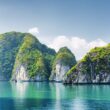 Beautiful azure water of lagoon in the Halong Bay (Descending Dragon Bay) at the Gulf of Tonkin of the South China Sea, Vietnam. Scenic landscape formed by karst towers-isles on blue sky background.
