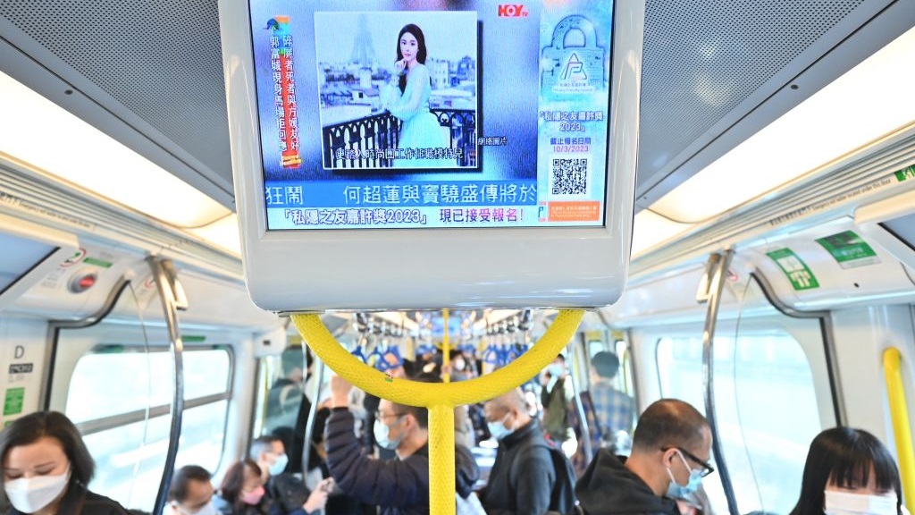 People watch a screen on a train showing news about Hong Kong model and influencer Abby Choi