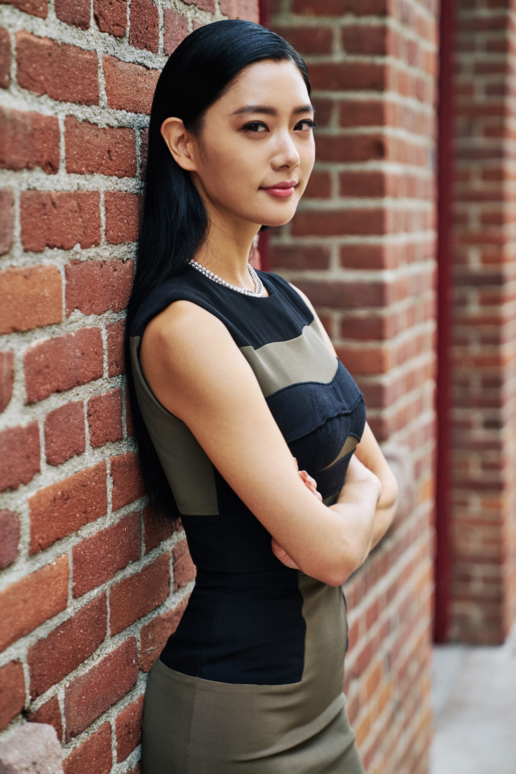 Clara Lee standing beside a brick wall