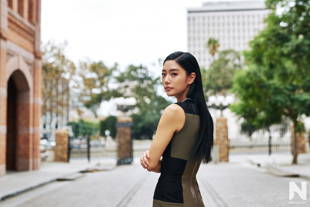 Clara Lee looking over her shoulder on a tree-lined street